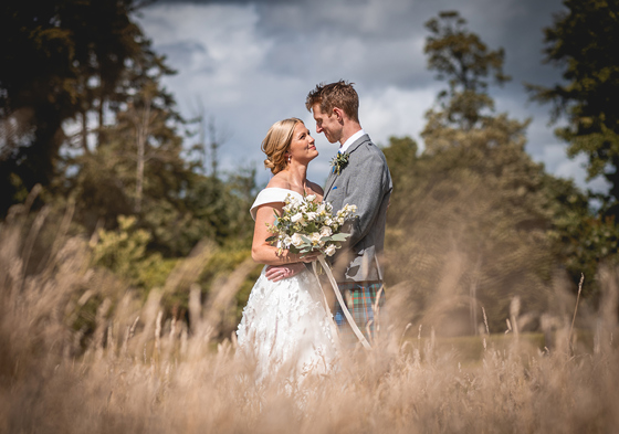 Bride and groom in field embrace